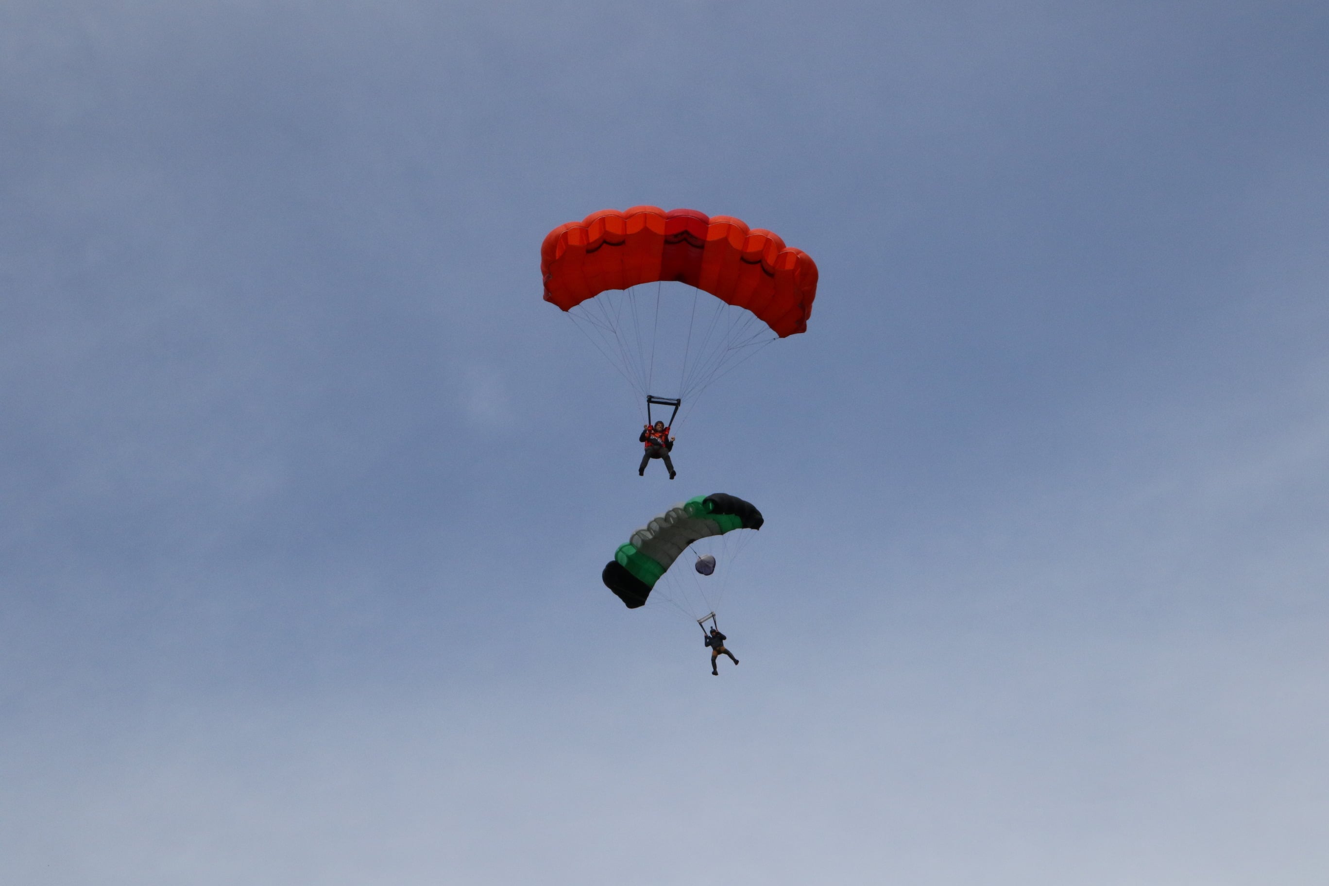 two base jumpers with parachutes fall through open sky
