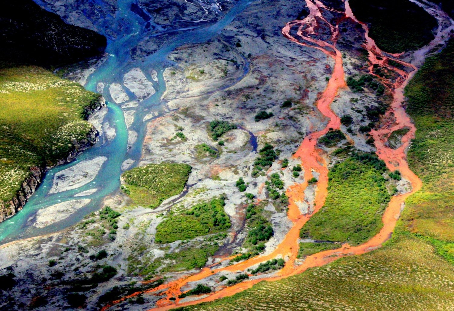 An aerial view of the rust-colored Kutuk River in Gates of the Arctic National Park in Alaska. Thawing permafrost is exposing minerals to weathering, increasing the acidity of the water, which releases metals like iron, zinc and copper/NPS, Ken Hill