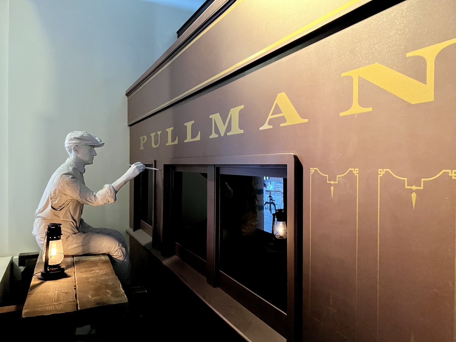 In the Pullman National Historical Park visitor center, a display shows a man hand painting a wooden Pullman railroad car.