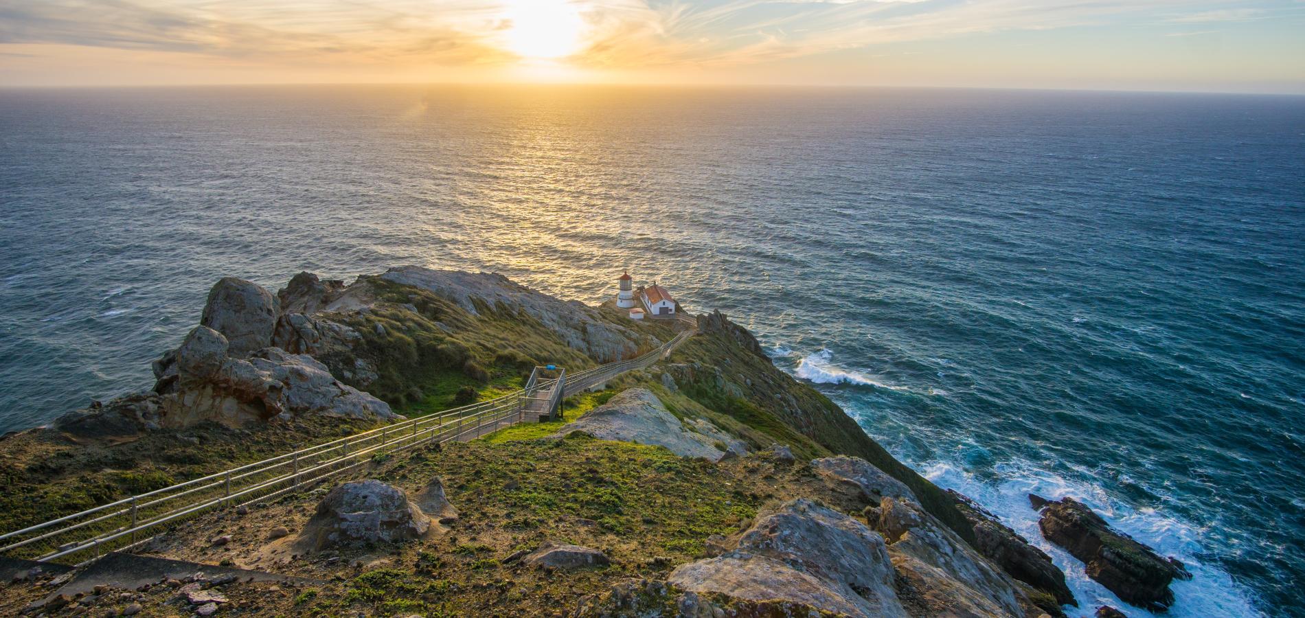 The historic Point Reyes Lighthouse and adjacent structures at the base of the 313-step stairway at sunset / NPS