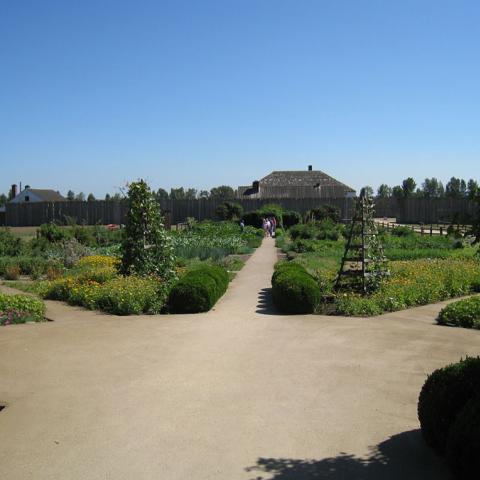 Pathways radiate from a central clearing in the formal, symmetrical garden. Bright flowers direct the view to the fort at Fort Vancouver National Historic Site.