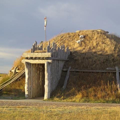 Life-sized earthlodge home with door facing east composed of wooden posts, dirt, and dried grass, Knife River Indian Villages National Historic Site