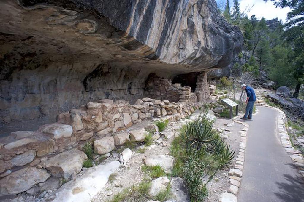 A paved trail next to a cliff dwelling within Walnut Canyon National Monument