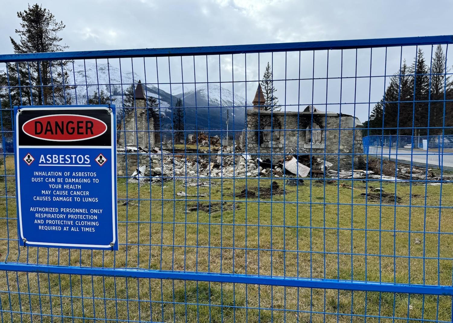 By the ruins of a church, a warning about asbestos serves as a stark reminder of the havoc a summer wildfire wreaked.