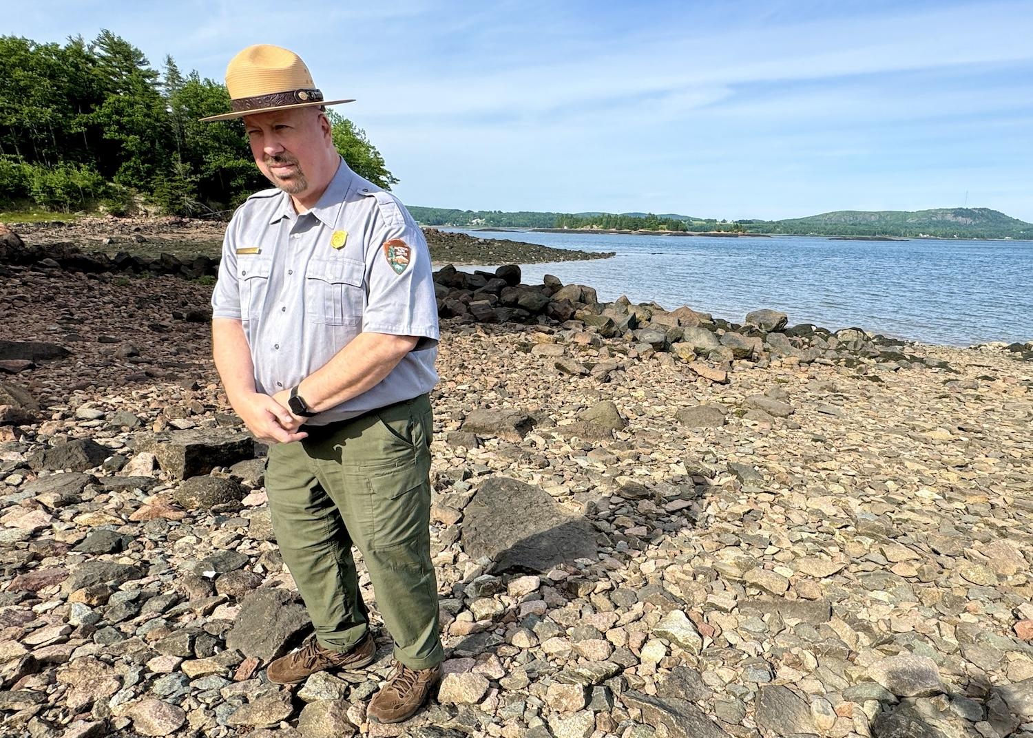 Michael Zwelling, site manager for Saint Croix Island National Historic Site in Maine, stands on the shore of the Saint Croix River in front of Saint Croix Island.