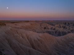Shades of blue, pink, and purple bathe the sky and landscape at Burns Basin Overlook in Badlands National Park.
