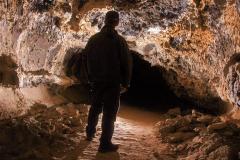 Cave Specialist Shane Fryer looking through a side tube of Catacombs Cave, Lava Beds National Monument