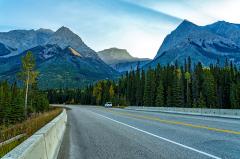 A parked SUV along the road in front of towering mountains early in the morning, Yoho National Park, British Columbia, Canada